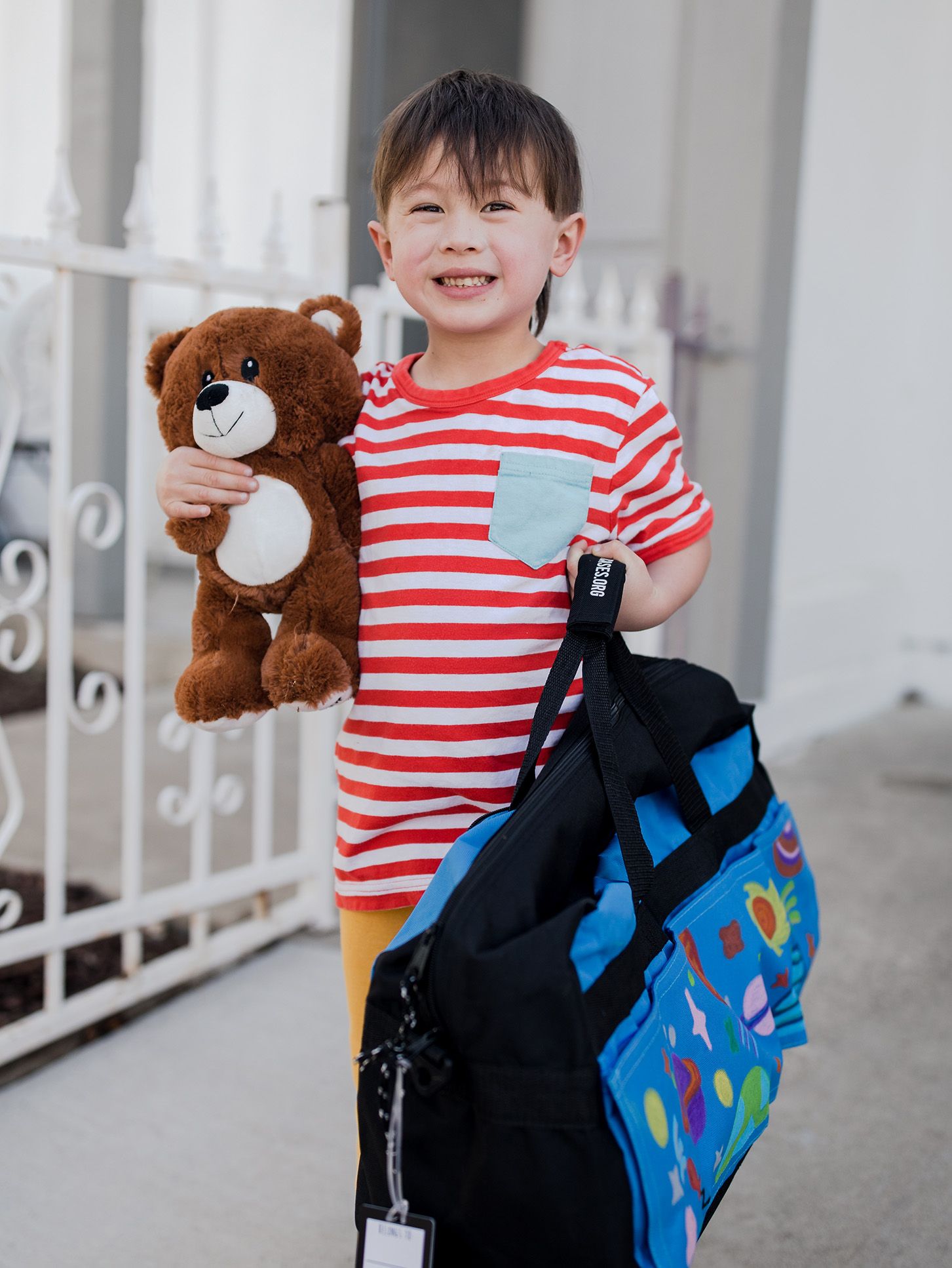 Little boy holding a teddy bear and sweetcase